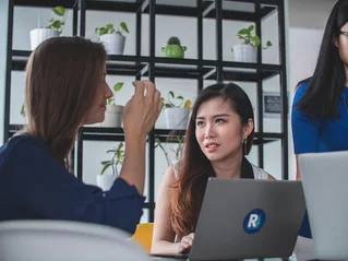 three women talking around computers