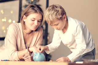 mother and son putting coin in piggy bank