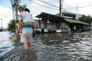 person piggybacking child through flood