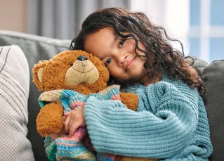 girl snuggling teddy bear
